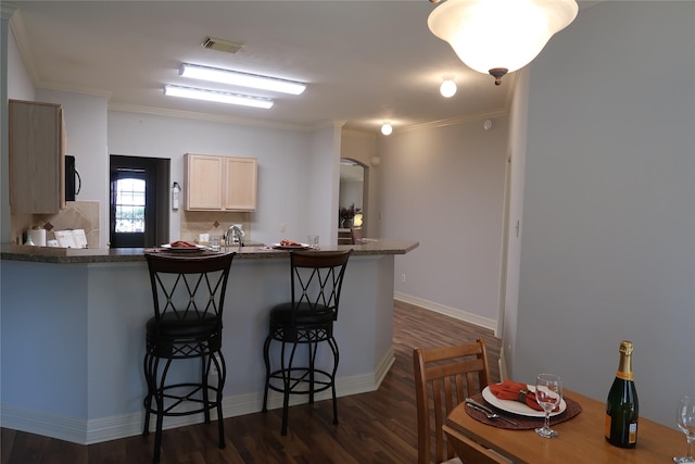 1714 Oak Ridge Dr, Kemah, TX 77565 - kitchen with a kitchen breakfast bar, a peninsula, dark wood-style floors, ornamental molding, and dark countertops