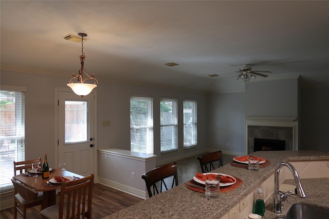 1714 Oak Ridge Dr, Kemah, TX 77565 - dining room featuring a tiled fireplace, a ceiling fan, crown molding, and wood finished floors