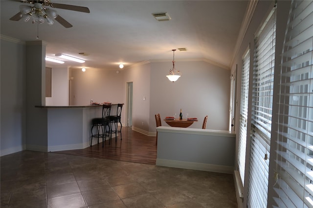 1714 Oak Ridge Dr, Kemah, TX 77565 - kitchen featuring ornamental molding, vaulted ceiling, a ceiling fan, a kitchen bar, and decorative light fixtures
