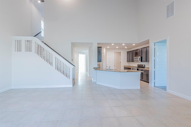 12610 Marley Hills Trl, Houston, TX 77089 - kitchen with stainless steel appliances, a towering ceiling, open floor plan, dark brown cabinetry, and light tile patterned flooring