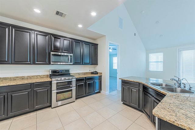 12610 Marley Hills Trl, Houston, TX 77089 - kitchen featuring appliances with stainless steel finishes, light tile patterned floors, dark cabinets, vaulted ceiling, and recessed lighting