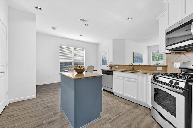 31 Hearthwick Rd, Tomball, TX 77375 - kitchen with stainless steel appliances, wood finish floors, white cabinetry, backsplash, and recessed lighting