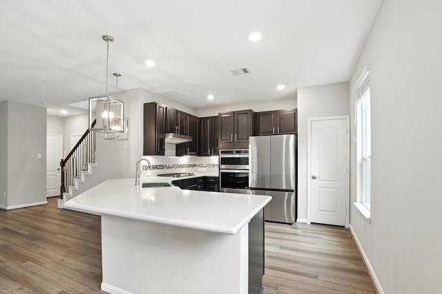 8618 Cedar Plains Ln, Houston, TX 77080 - kitchen with stainless steel appliances, dark brown cabinets, light wood-type flooring, light countertops, and recessed lighting