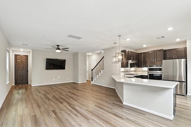 8618 Cedar Plains Ln, Houston, TX 77080 - kitchen featuring appliances with stainless steel finishes, dark brown cabinetry, light wood-style floors, recessed lighting, and light countertops