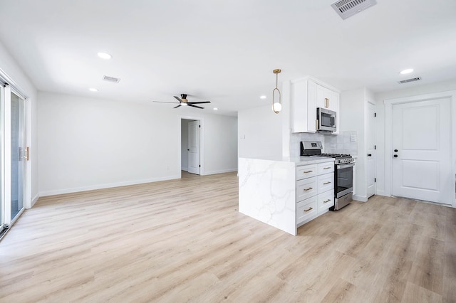 5730 Alvarado Dr, Houston, TX 77035 - kitchen with stainless steel appliances, ceiling fan, light stone counters, light wood finished floors, and white cabinets