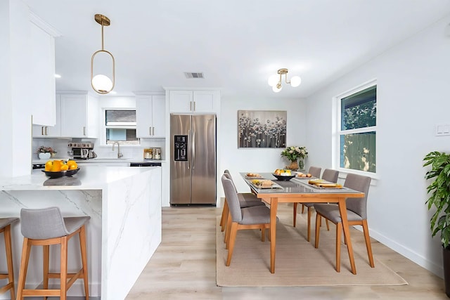 5730 Alvarado Dr, Houston, TX 77035 - kitchen featuring stainless steel fridge with ice dispenser, white cabinets, a breakfast bar, and light wood-style flooring