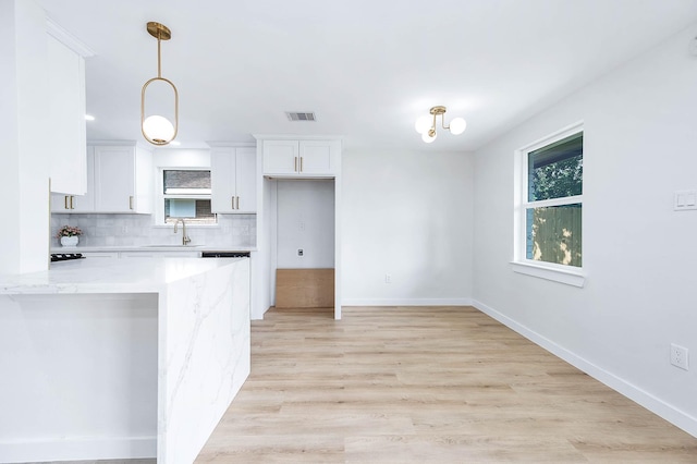 5730 Alvarado Dr, Houston, TX 77035 - kitchen featuring white cabinets, tasteful backsplash, light stone countertops, hanging light fixtures, and light wood finished floors