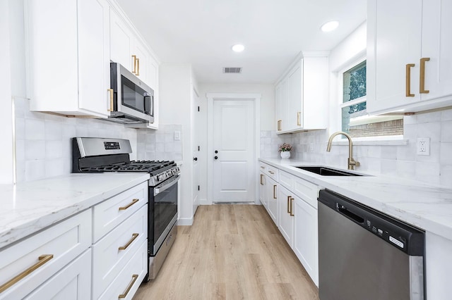 5730 Alvarado Dr, Houston, TX 77035 - kitchen with appliances with stainless steel finishes, white cabinets, light wood-style flooring, light stone counters, and recessed lighting