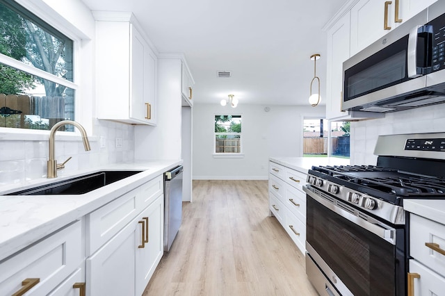 5730 Alvarado Dr, Houston, TX 77035 - kitchen featuring stainless steel appliances, backsplash, light wood-style flooring, white cabinetry, and light stone countertops