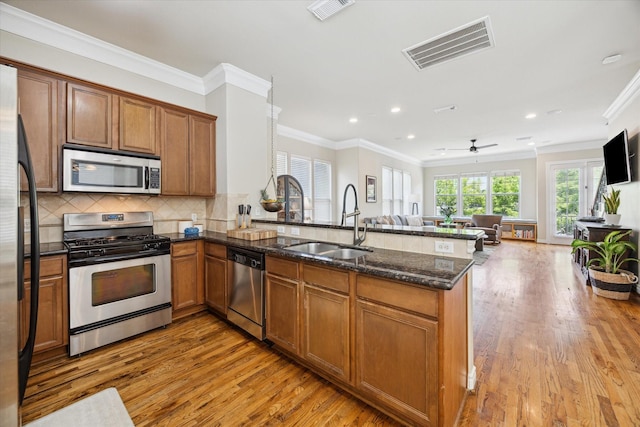 1219 Hickory St, Houston, TX 77007 - kitchen with appliances with stainless steel finishes, open floor plan, light wood finished floors, brown cabinetry, and a peninsula