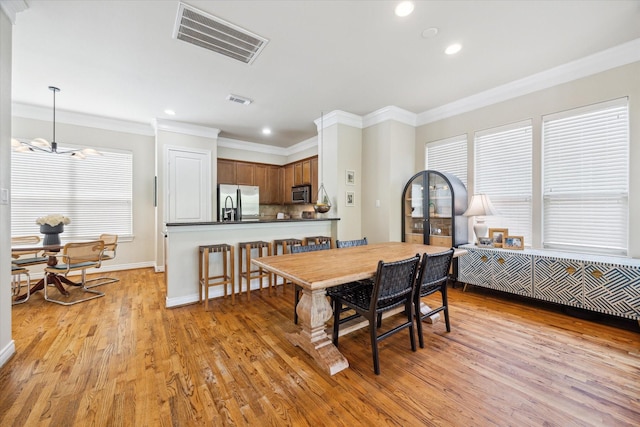 1219 Hickory St, Houston, TX 77007 - dining room with light wood finished floors, crown molding, recessed lighting, and a chandelier