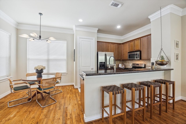 1219 Hickory St, Houston, TX 77007 - kitchen featuring appliances with stainless steel finishes, light wood-type flooring, tasteful backsplash, a peninsula, and a breakfast bar area