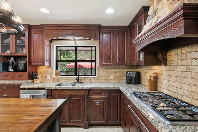 1025 Creek Bnd, Jasper, TX 75951 - kitchen with stainless steel gas stovetop, custom exhaust hood, wood counters, decorative backsplash, and glass insert cabinets