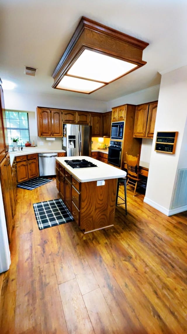 1600 Azalea St, Sweeny, TX 77480 - kitchen featuring black appliances, a center island, light wood finished floors, light countertops, and brown cabinetry