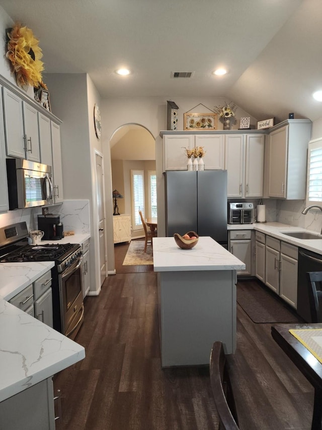 3514 Tulip Trace Dr, Spring, TX 77386 - kitchen with stainless steel appliances, arched walkways, gray cabinets, dark wood-style flooring, and light stone counters