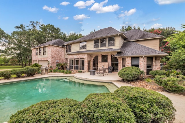 1019 Towering Oaks St, Magnolia, TX 77355 - back of house featuring a patio area, brick siding, roof with shingles, and an outdoor pool