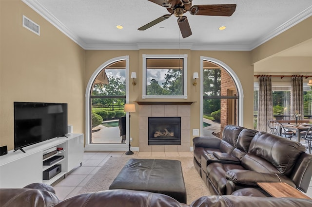 1019 Towering Oaks St, Magnolia, TX 77355 - living area featuring a tiled fireplace, healthy amount of natural light, ceiling fan, light tile patterned floors, and crown molding