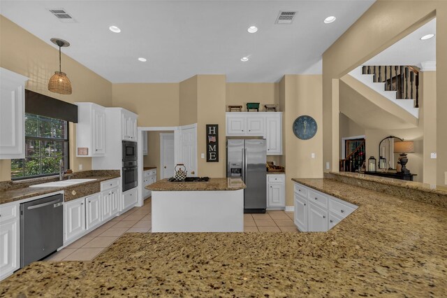 1019 Towering Oaks St, Magnolia, TX 77355 - kitchen with appliances with stainless steel finishes, light tile patterned flooring, dark stone countertops, white cabinets, and a kitchen island
