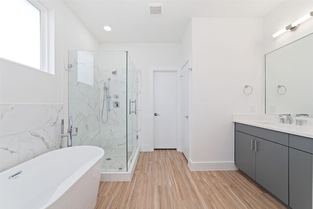 2103 Holman, Houston, TX 77004 - bathroom featuring a freestanding tub, a marble finish shower, vanity, and wood finished floors