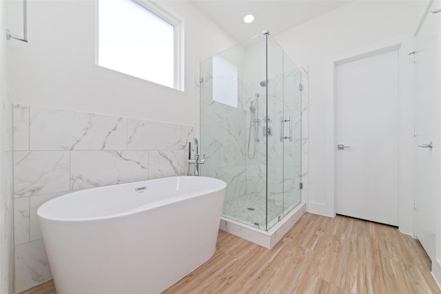 2103 Holman, Houston, TX 77004 - full bathroom featuring a marble finish shower, a soaking tub, tile walls, wood finished floors, and a wainscoted wall
