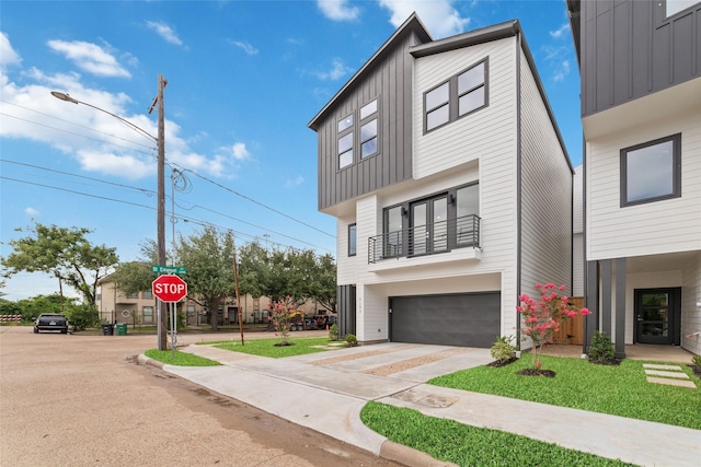 2103 Holman, Houston, TX 77004 - modern home featuring board and batten siding, an attached garage, concrete driveway, and a balcony