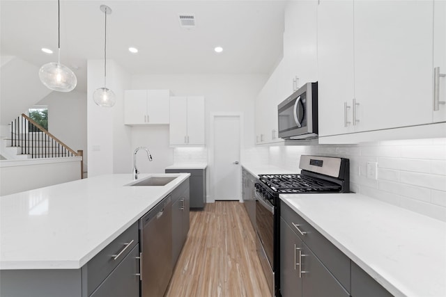 2103 Holman, Houston, TX 77004 - kitchen with appliances with stainless steel finishes, light wood-style flooring, light countertops, white cabinets, and recessed lighting