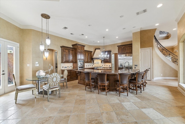 15611 Oyster Cove Dr, Sugar Land, TX 77478 - kitchen with stainless steel appliances, a large island with sink, a kitchen breakfast bar, stone tile floors, and crown molding