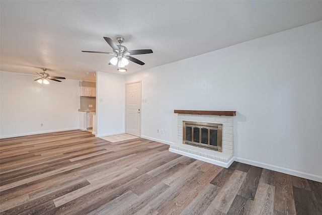 2110 Wilcrest Dr Unit 140, Houston, TX 77042 - unfurnished living room with ceiling fan, wood finished floors, and a brick fireplace