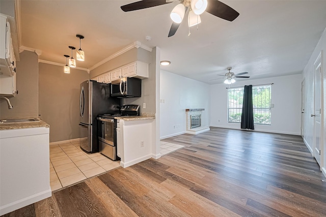 2110 Wilcrest Dr Unit 140, Houston, TX 77042 - kitchen featuring stainless steel appliances, ceiling fan, white cabinets, light wood finished floors, and crown molding