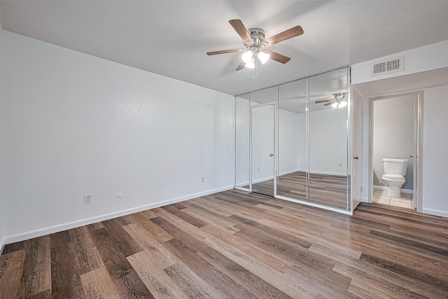 2110 Wilcrest Dr Unit 140, Houston, TX 77042 - unfurnished bedroom featuring wood finished floors, connected bathroom, a closet, and a ceiling fan