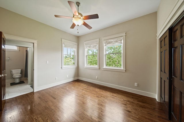 959 W 42nd St, Houston, TX 77018 - unfurnished bedroom featuring multiple windows, wood finished floors, ensuite bathroom, and ceiling fan