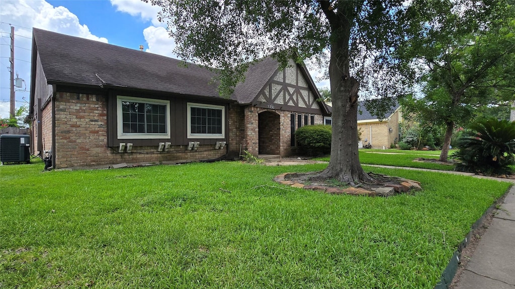 4531 Hickory Downs Dr, Houston, TX 77084 - tudor-style house with brick siding, a front lawn, and a shingled roof
