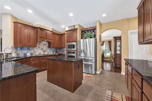 5806 Wilton St, Pearland, TX 77584 - kitchen featuring stainless steel appliances, arched walkways, backsplash, dark stone counters, and recessed lighting
