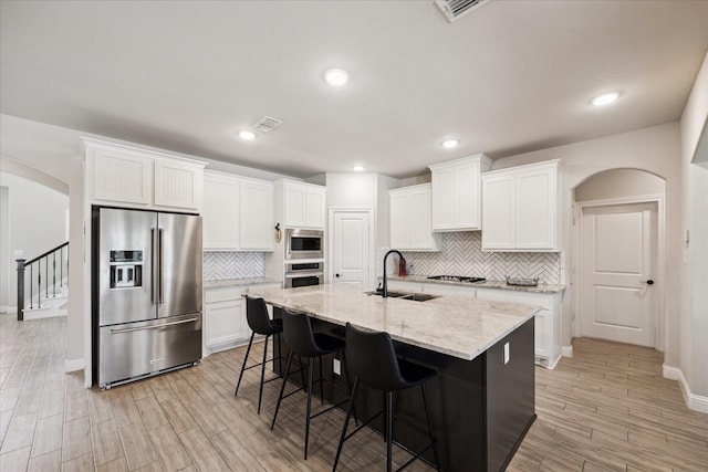 508 Buckhorn St, Sealy, TX 77474 - kitchen featuring stainless steel appliances, backsplash, white cabinets, a breakfast bar area, and recessed lighting