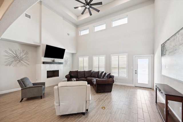 508 Buckhorn St, Sealy, TX 77474 - living room featuring light wood-style floors, a tile fireplace, a high ceiling, and a ceiling fan