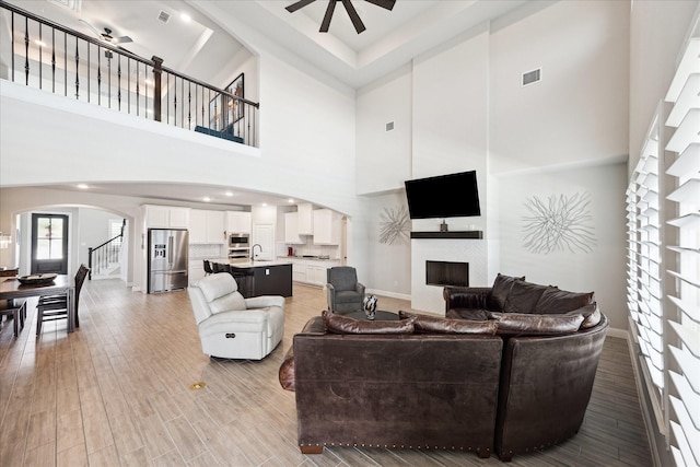 508 Buckhorn St, Sealy, TX 77474 - living area with ceiling fan, arched walkways, a fireplace, a towering ceiling, and stairway