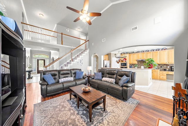 12815 Mimosa Spring Dr, Tomball, TX 77377 - living area with arched walkways, a ceiling fan, high vaulted ceiling, light wood-style flooring, and stairs