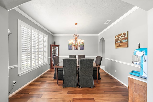12815 Mimosa Spring Dr, Tomball, TX 77377 - dining space with arched walkways, wood finished floors, a chandelier, a textured ceiling, and ornamental molding