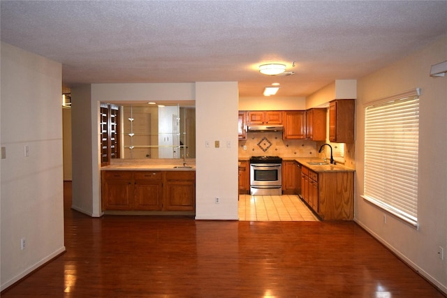 2926 Field Line Dr, Sugar Land, TX 77479 - kitchen featuring stainless steel range oven, brown cabinets, under cabinet range hood, and light wood-style floors