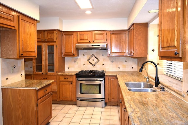 2926 Field Line Dr, Sugar Land, TX 77479 - kitchen featuring stainless steel range with gas stovetop, under cabinet range hood, brown cabinets, light stone counters, and recessed lighting