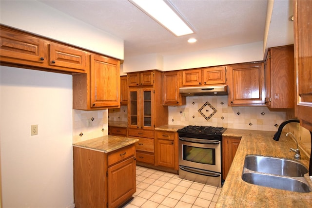 2926 Field Line Dr, Sugar Land, TX 77479 - kitchen featuring stainless steel gas range oven, under cabinet range hood, brown cabinets, tasteful backsplash, and recessed lighting