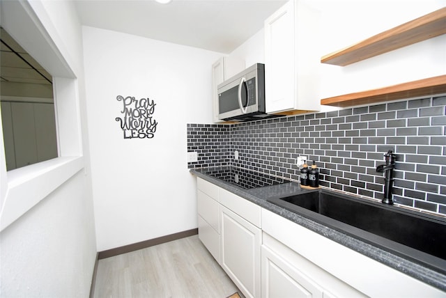 14306 Waterville Way, Houston, TX 77015 - kitchen with stainless steel microwave, dark countertops, tasteful backsplash, white cabinets, and black electric stovetop