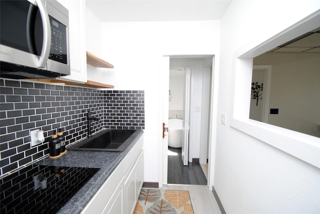 14306 Waterville Way, Houston, TX 77015 - kitchen with stainless steel microwave, dark countertops, tasteful backsplash, and white cabinetry
