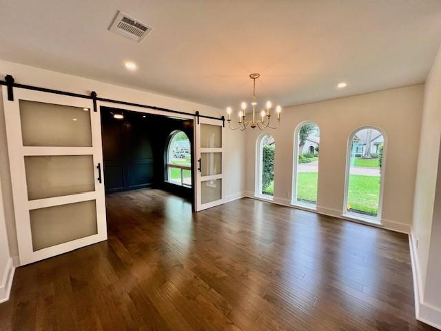 2823 Stetson Ln, Houston, TX 77043 - unfurnished dining area featuring a barn door, healthy amount of natural light, dark wood-style flooring, a chandelier, and recessed lighting