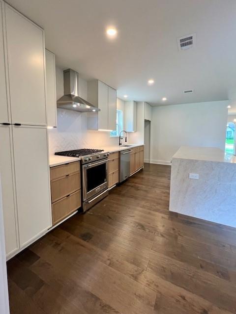 2823 Stetson Ln, Houston, TX 77043 - kitchen featuring wall chimney exhaust hood, appliances with stainless steel finishes, dark wood-style floors, recessed lighting, and light countertops
