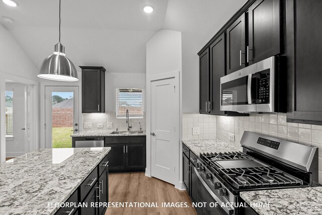 20626 Draper Rd, Tomball, TX 77377 - kitchen with appliances with stainless steel finishes, lofted ceiling, dark cabinetry, light stone countertops, and light wood-type flooring