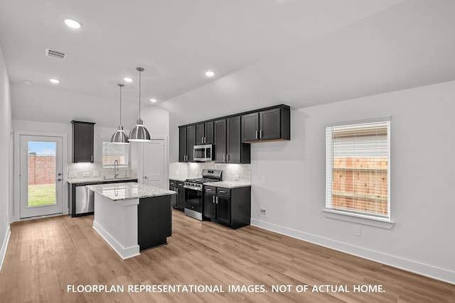 20626 Draper Rd, Tomball, TX 77377 - kitchen featuring stainless steel appliances, decorative backsplash, vaulted ceiling, light stone counters, and a center island