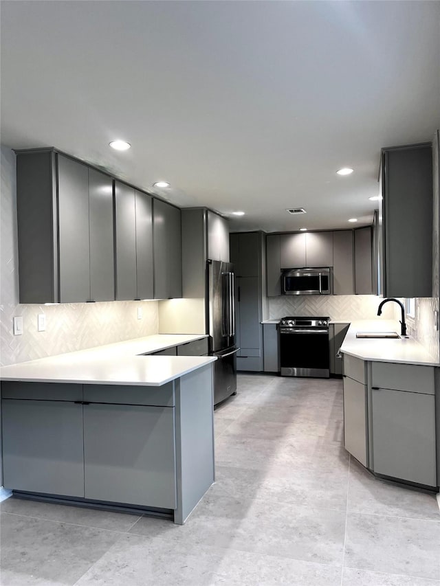 142 Beverly Ln, Bellaire, TX 77401 - kitchen featuring stainless steel appliances, gray cabinets, tasteful backsplash, a peninsula, and light countertops