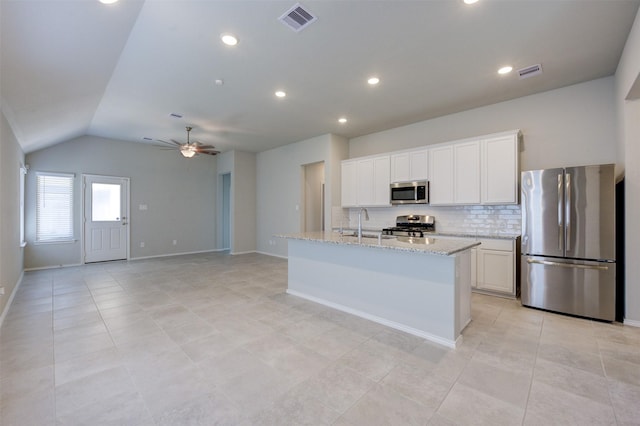 32014 Quail Terrace Ln, Conroe, TX 77385 - kitchen with stainless steel appliances, a ceiling fan, backsplash, white cabinetry, and an island with sink
