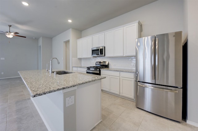 32014 Quail Terrace Ln, Conroe, TX 77385 - kitchen featuring stainless steel appliances, ceiling fan, decorative backsplash, an island with sink, and white cabinetry